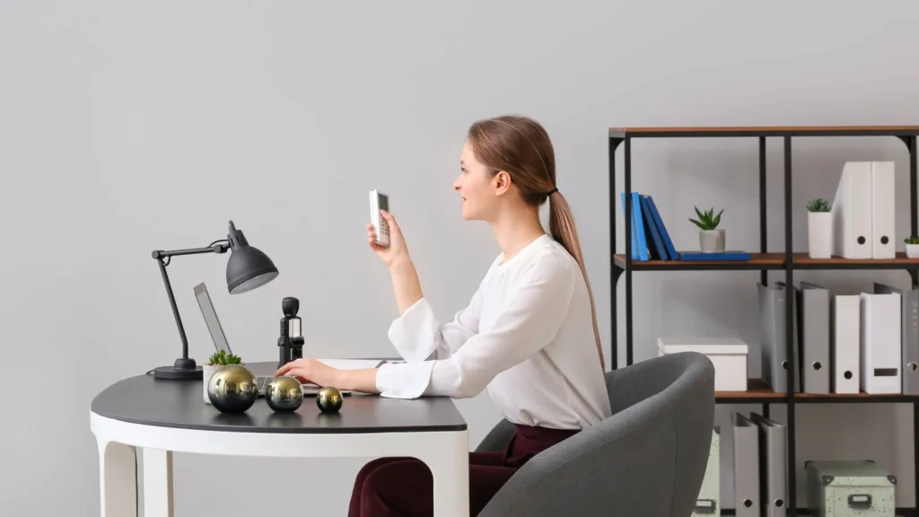 Woman using remote to control air conditioner – best aircon brands Melbourne 2025.